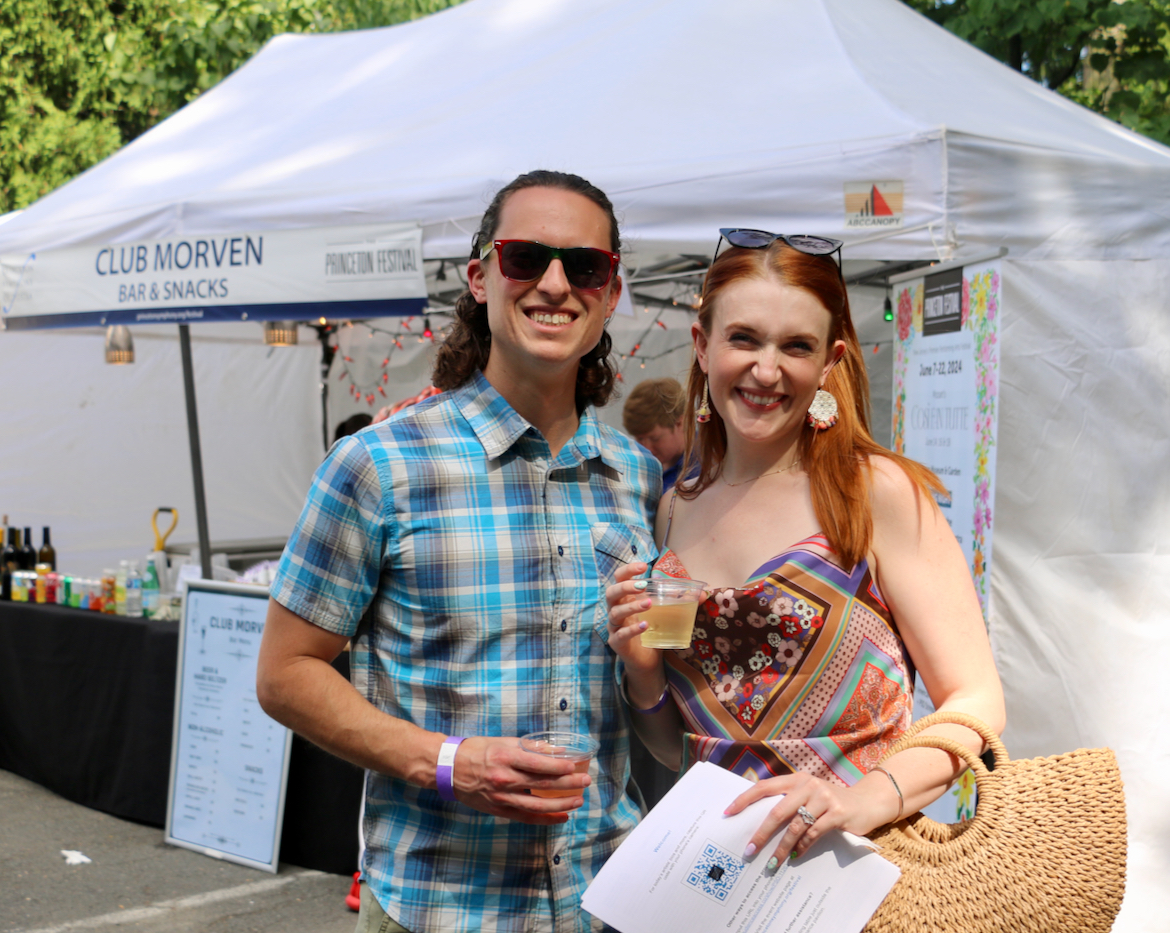 Two patrons smiling in front of a white tent with text: Club Morven Bar & Snacks