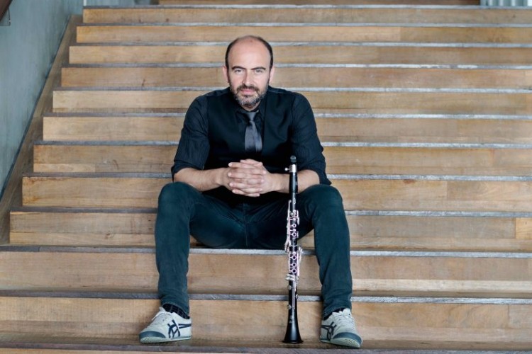 Kinan Azmeh seated on a staircase with a clarinet