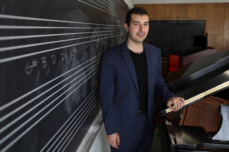 Saad Haddad standing between a chalkboard a piano