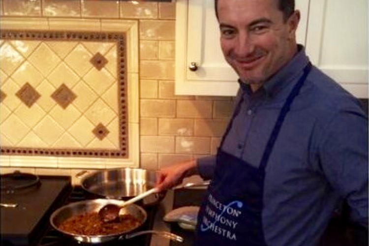 Rossen Milanov cooking in the kitchen with a PSO apron on