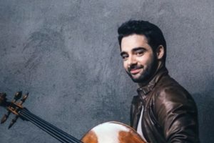 Pablo Ferràndez smiles and holds a cello under his arm