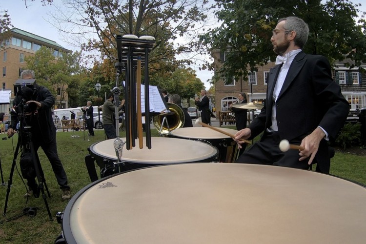PSO Timpani player Jeremy Levine plays the Timpani. To his left, another man is filming with a camera on a tripod.