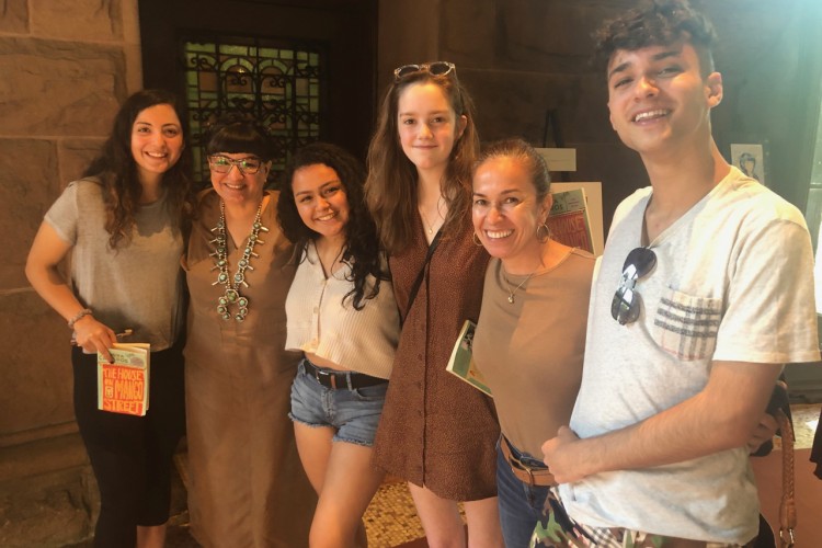 Group of 5 young adults standing with Sandra Cisneros.
