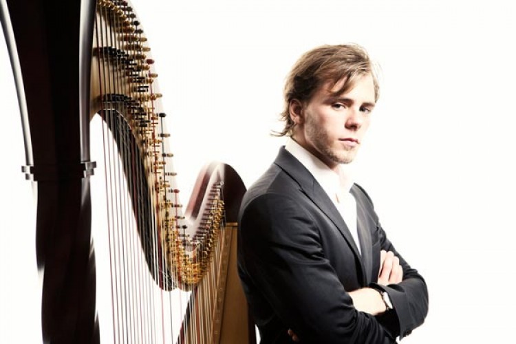 Alexander Boldachev stands back to back against a harp