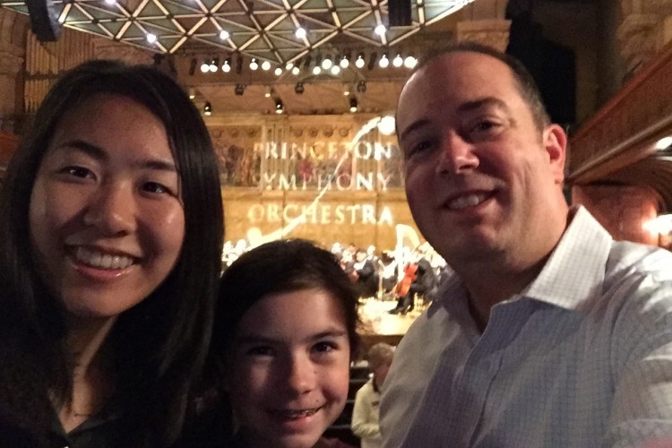 Mother and Father with daughter stood between at a concert.