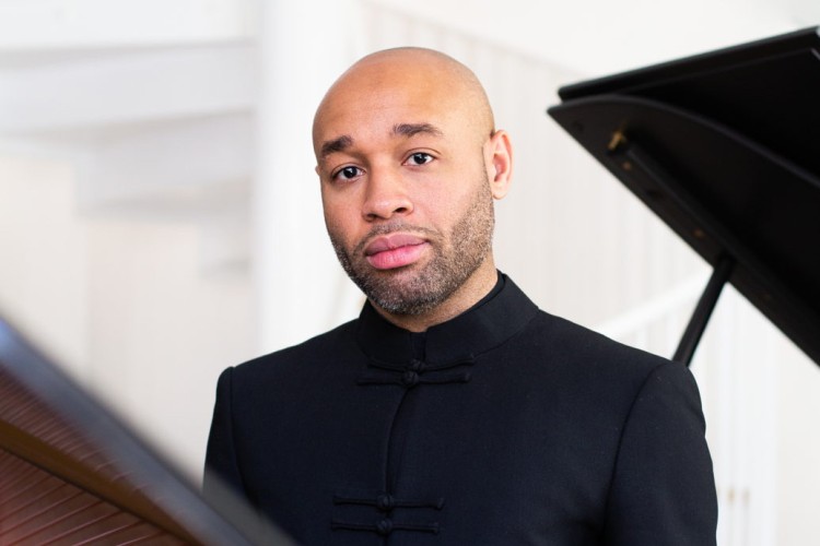 Man standing in front of a grand piano.