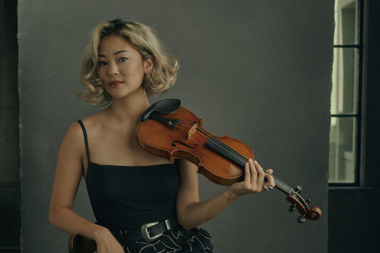 Simone Porter - Holding violin, wearing a belted, black and white outfit