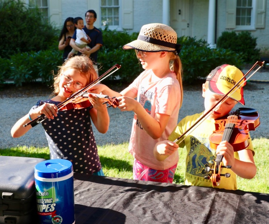 Children playing violins at Festival instrument petting zoo