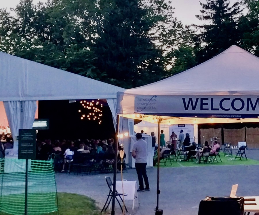 Outdoor Festival tented entrance with two staff members; text: Welcome