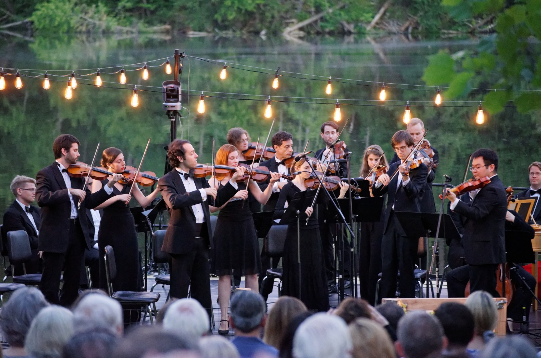 The Sebastians performing outdoors in a garden-like setting below string lights.