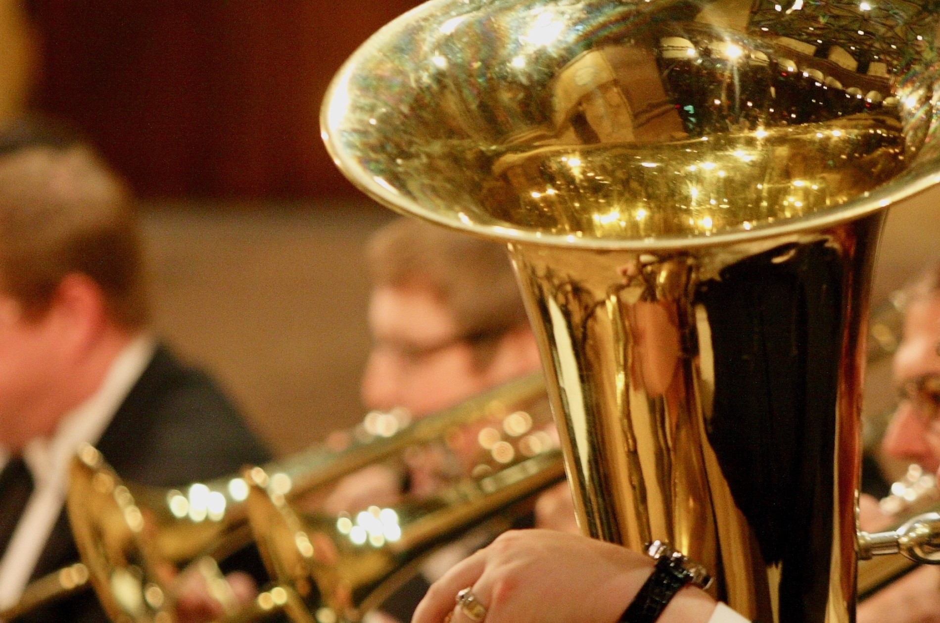 Tuba and trombones with obscured players' faces. 