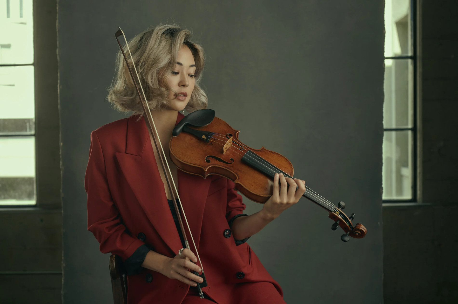 Simone Porter - Holding violin, wearing a dark red suit